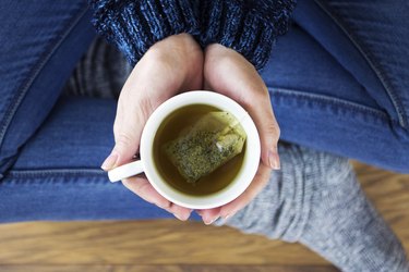top view of a woman drinking herbal tea, as a natural remedy for gas