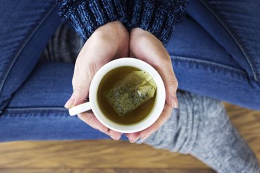 顶视图的女人拿着杯花草茶作为气体的自然疗法