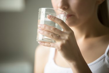 A person sipping a glass of salt water, as a toothache remedy