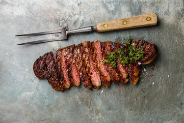 Sliced steak with chimichurri sauce and meat fork
