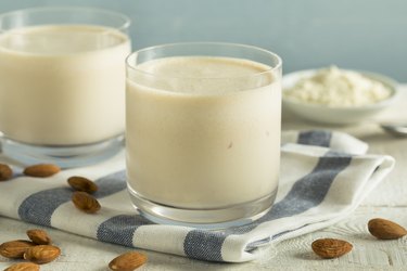 Two glasses of almond milk on a striped towel