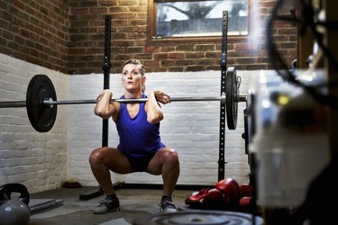 Woman exercising in home gym in converted garage performing a squat or clean