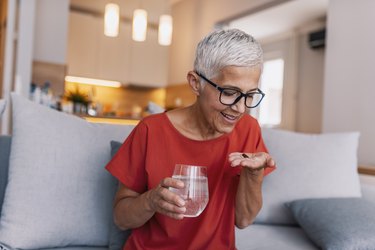 Woman holding glass of water taking pill