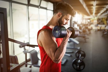 Determined male working out in gym lifting weights