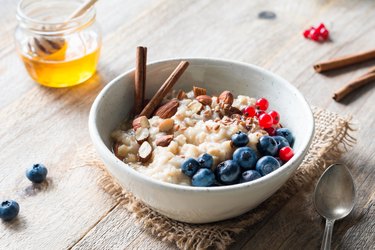 Oatmeal porridge bowl with fruits, nuts and cinnamon in bowl