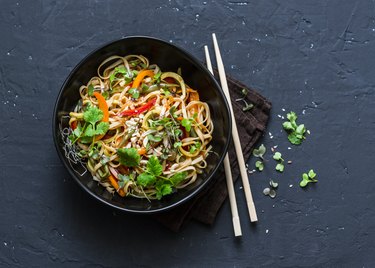 泰式素食蔬菜乌冬面条在一个黑暗的背景,高级视图。素食在亚洲风格。本空间