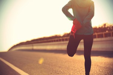 young fitness woman runner stretching legs before run