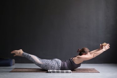 Woman practicing yoga, stretching in Salabhasana exercise, Double Leg Kicks pose