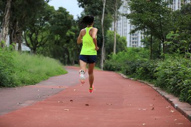 Fitness sporty woman jogger running at outdoors jogging track in park