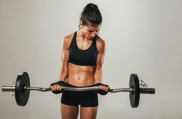 Strong young woman lifting barbell