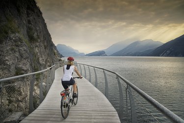 女性旅游自行车骑着现代加尔达湖周围循环路径