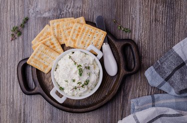 Traditional soft cheese with thyme and crackers on plate