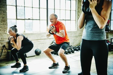 两个老年人做kettlebell锻炼在健身房