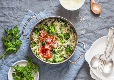 One pot orzo primavera. Orzo pasta with asparagus, broccoli, green peas and cream in a saucepan.