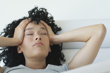 Young woman holding her head, eyes closed