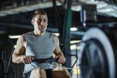 Mid adult male athlete concentrating while rowing at the gym