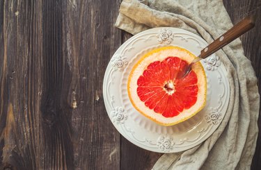 Half a grapefruit on vintage plate with spoon