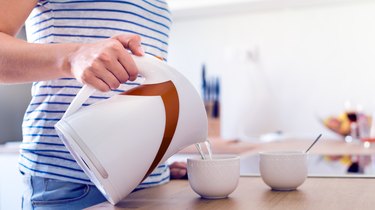 Woman preparing coffee or tea. Pouring water into a cup.