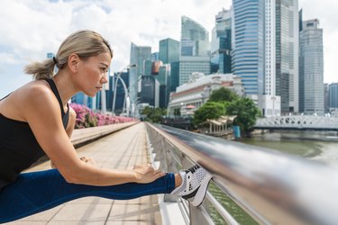 portrait of young Asian woman doing stretching before running in city