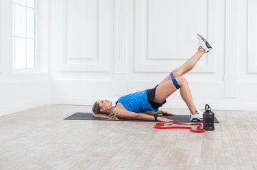 Side view of woman in sportswear with resistance bands training weak glutes