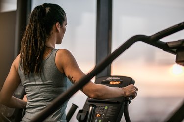 Athletic woman exercising on cross trainer in a health club.