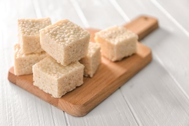 Wooden cutting board with rice treats on white table