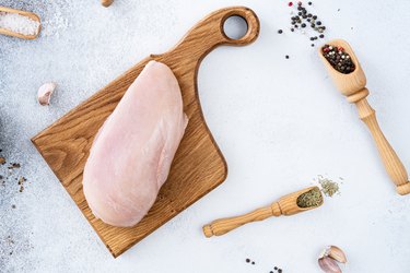 Top view of raw chicken meat on a black slate on the table. Raw chicken breast on a gray background