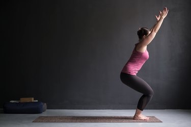 Woman practicing yoga, doing Chair exercise, Utkatasana pose, working out.