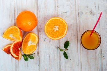 glass orange juice and a group oranges on white board