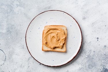 Toast with peanut butter and banana slices on an old gray concrete background. Top view.