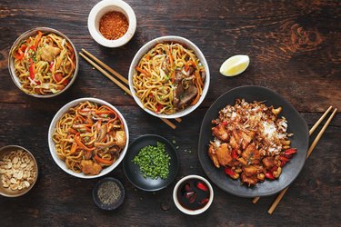 Bowls with chicken, beef and vegetables chow mein and rice with pork