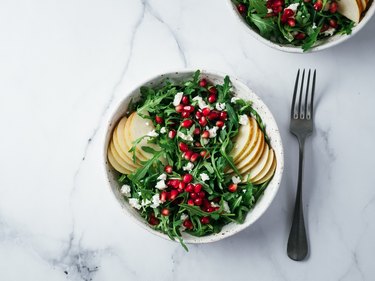 Vegan salad bowl with arugula, pear, pomegranate, cheese