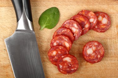 Chorizo Sausage sliced on a cutting board next to butcher knife.