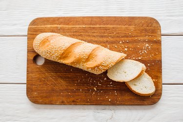 Crusty baguette on wooden board.