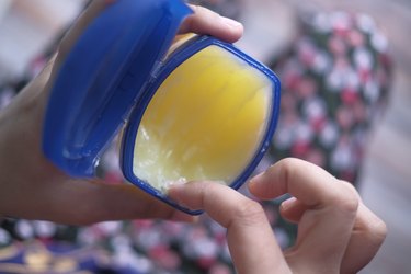 close view of a person reaching into a tub of vaseline, as a natural remedy for a yeast infection
