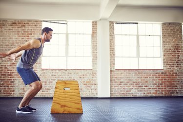 Male athlete doing box jumping at gym to build strength for runners