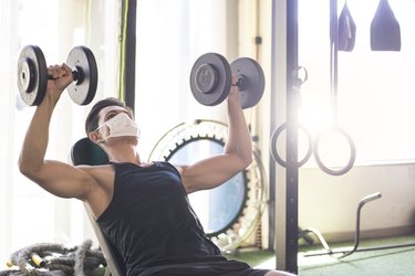 Man doing an incline chest press with dumbbells at the gym