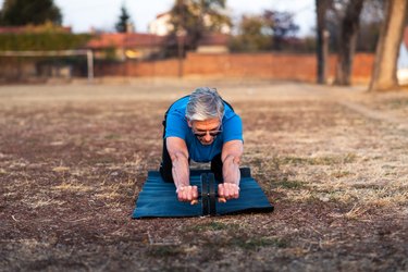 Senior doing workout with ab roller outdoors