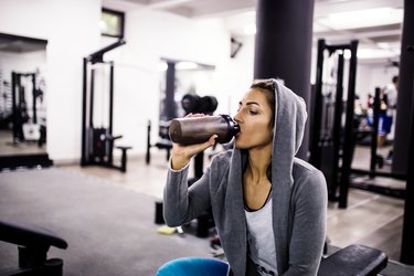 woman drinking a protein shake after a workout in the gym