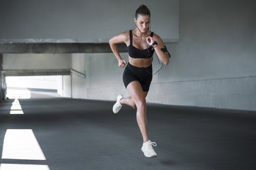 Young sportswoman running outdoors through concrete tunnel