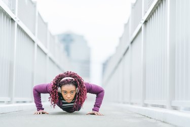 Determined sports woman doing push-ups in city