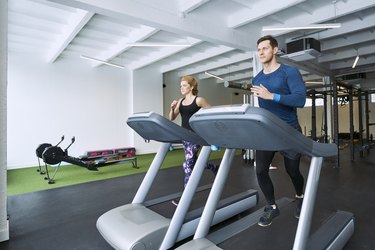 Man and woman running on treadmill at gym