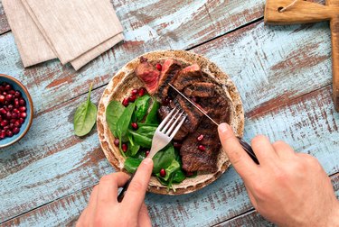 Man eats a beef grilled steak on wooden table. Rustic style