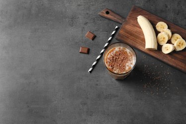 Glass with chocolate protein shake on table