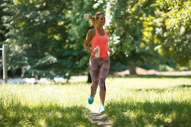 Young woman jogging outdoor at the park on beautiful summer day.