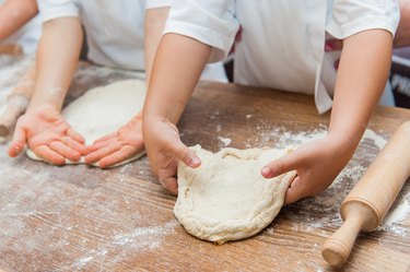 Young children make dough products. Hands closeup