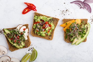 an assortment of avocado toast with veggies and nuts and seeds