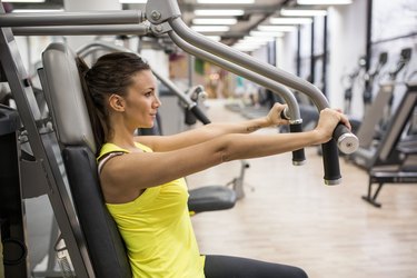 Young woman working out on exercise machine in a gym.