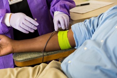 phlebotomist checking on patient donating blood before working out