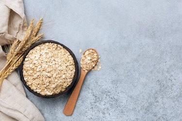 Bowl of rolled oats (oat flakes) on concrete background